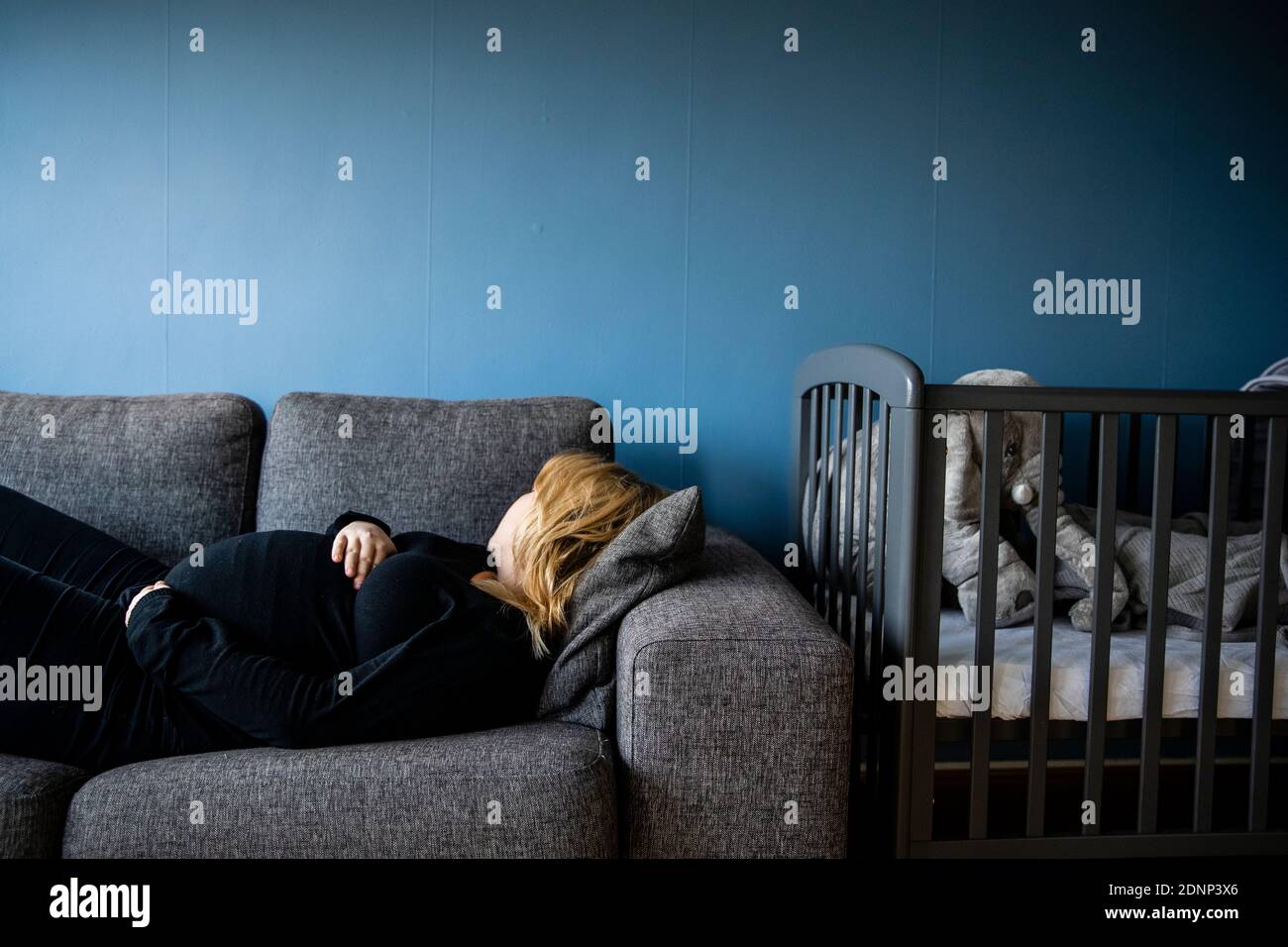 Donna incinta sdraiato sul divano Foto Stock