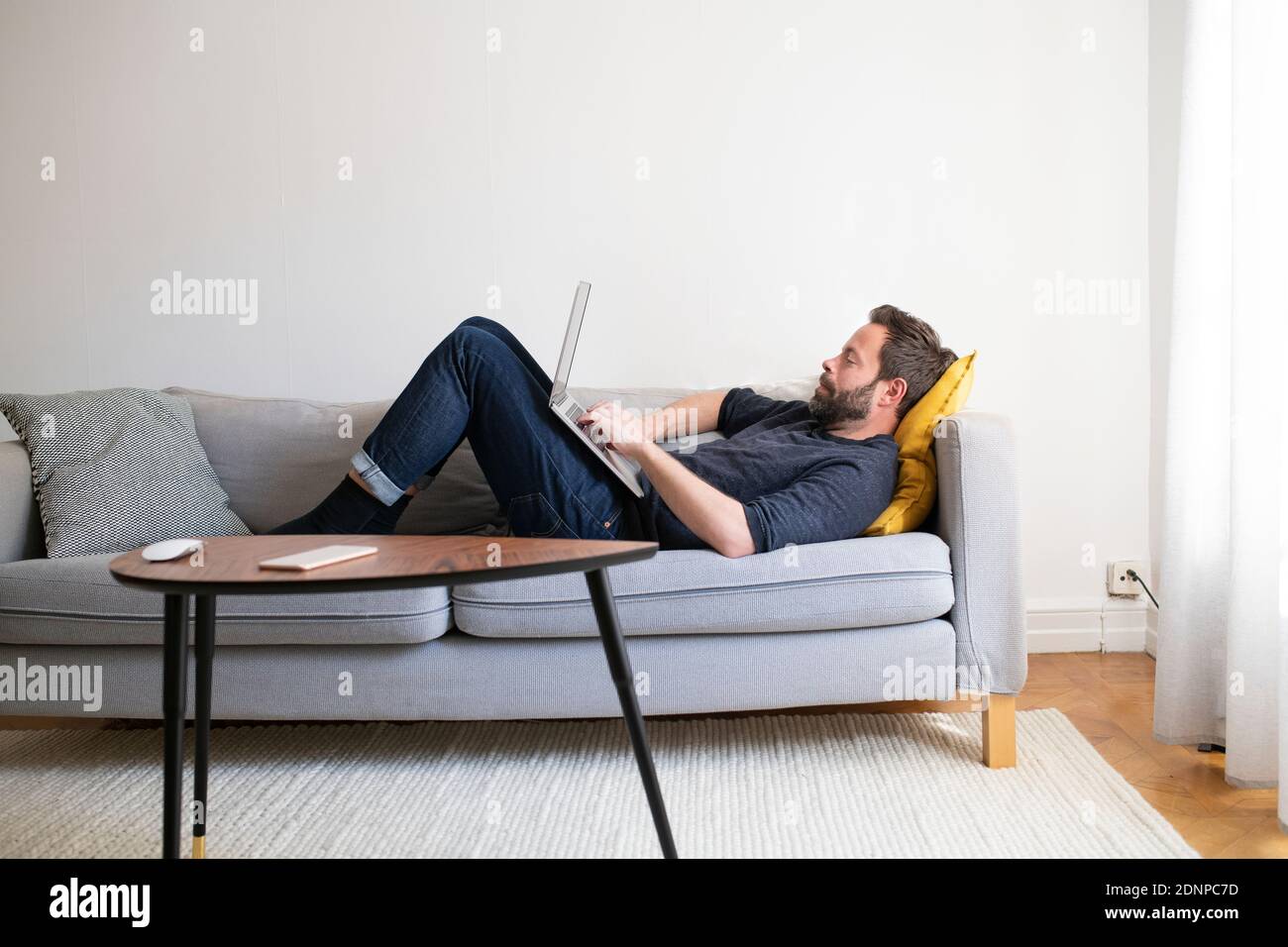 L'uomo sul divano con laptop Foto Stock
