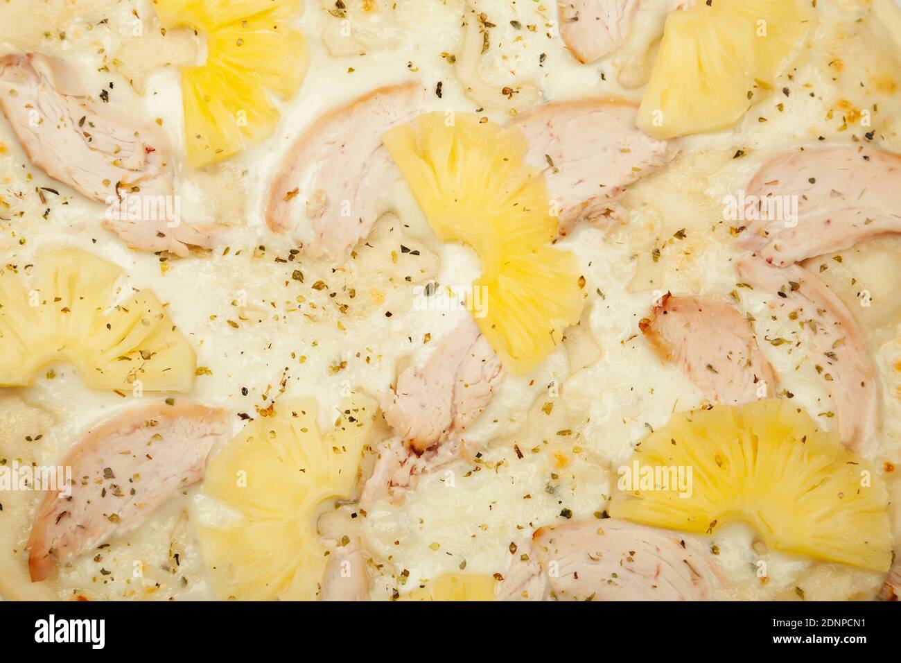 Texture deliziosa pizza hawaiana servita su un piatto di legno, ingredienti salsa all'aglio, mozzarella, pollo affumicato, ananas in scatola su bianco. Poster promozionale pizzeria. Foto Stock