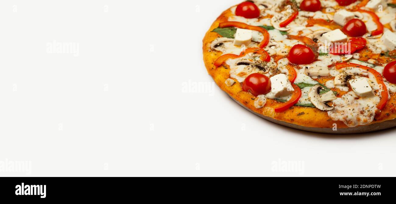 Deliziosa pizza vegetariana servita su un piatto di legno, gli ingredienti sono salsa di firma, basilico, mozzarella, champignons, peperoni, pomodori ciliegini, formaggio feta. Poster promozionale pizzeria. Foto Stock