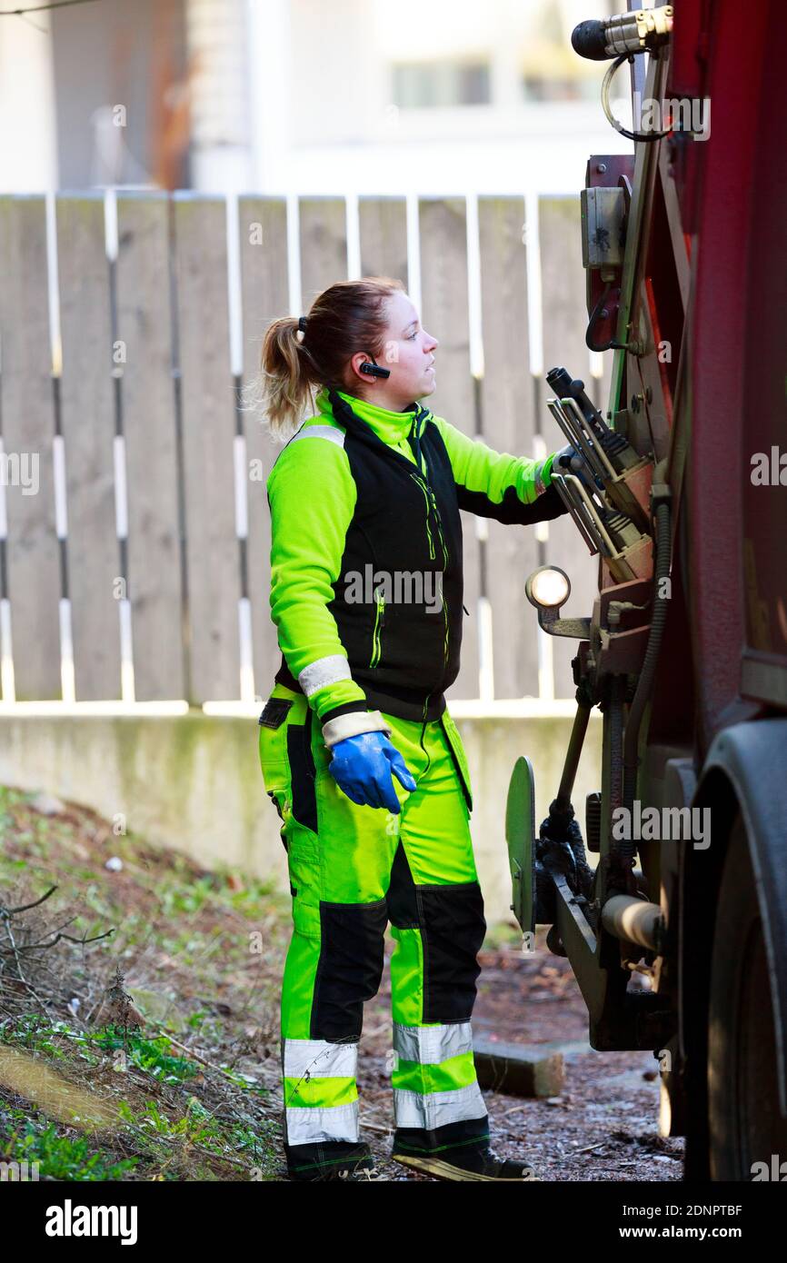 Donna che utilizza un veicolo per la raccolta rifiuti Foto Stock