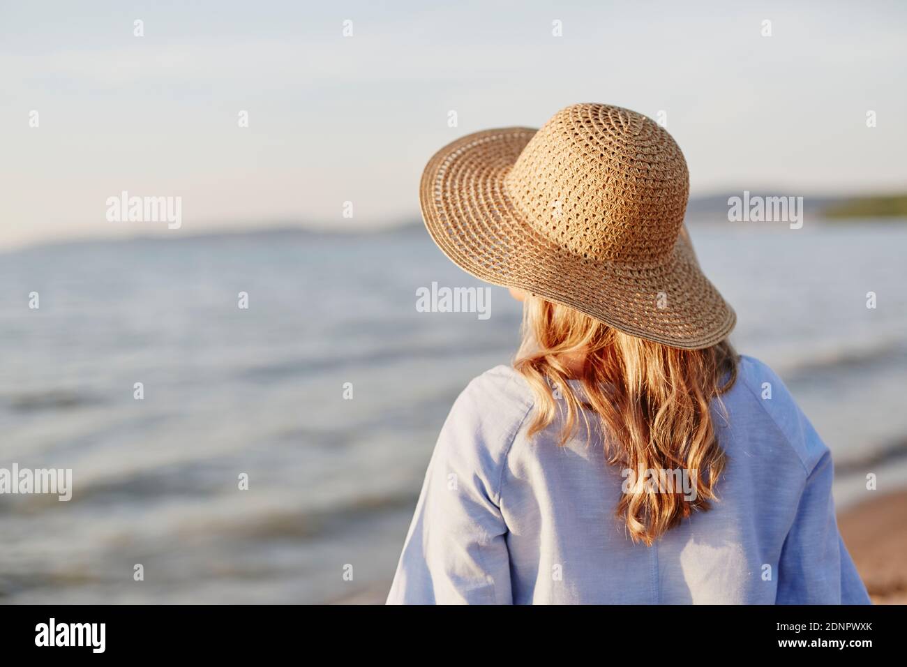 Donna che indossa cappello di paglia sulla spiaggia Foto Stock