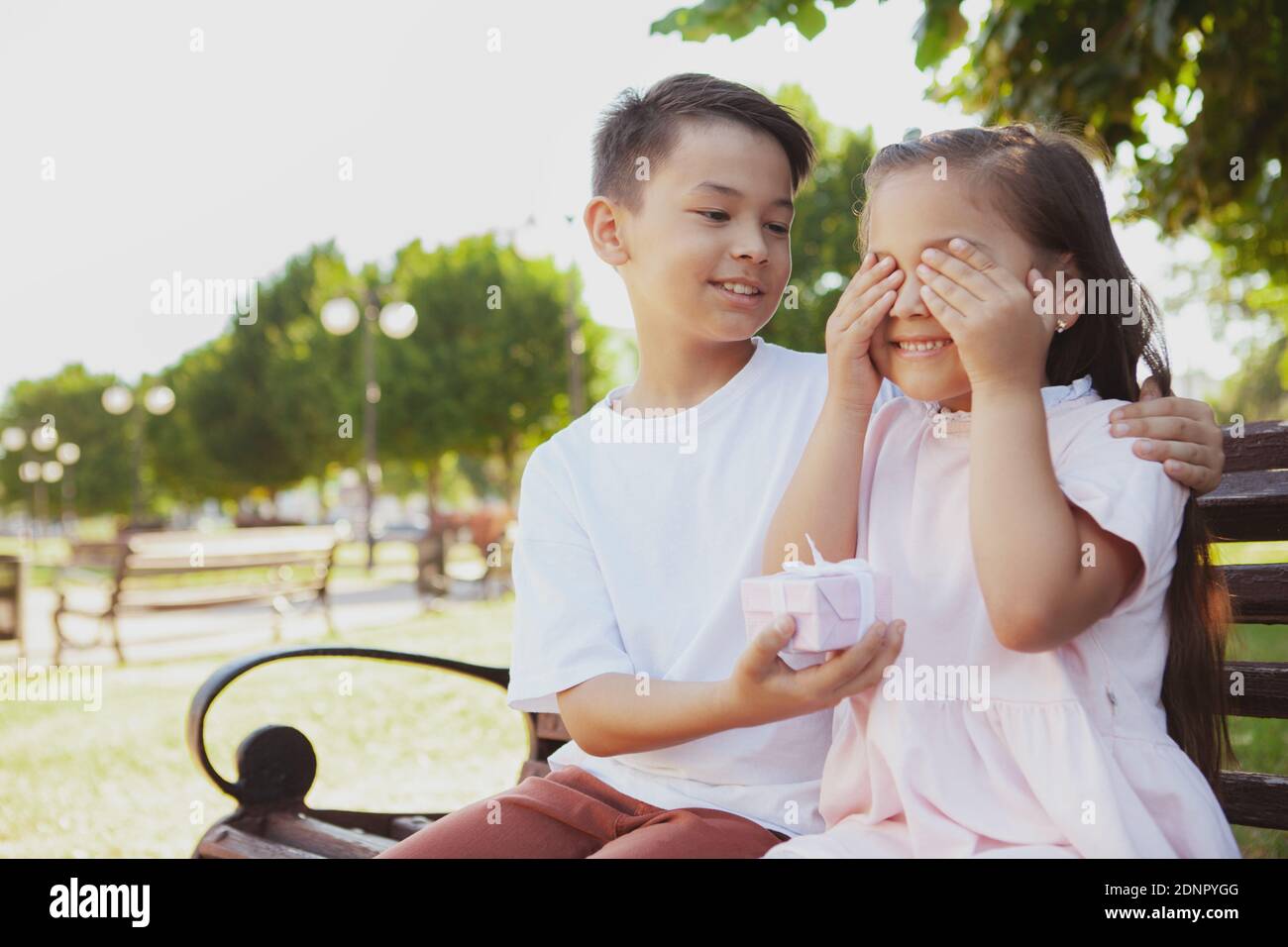 Carina bambina che riceve un regalo a sorpresa dal fratello. Felice giovane asiatico si congratula con la sua sorellina, dandole un regalo, copia spazio Foto Stock