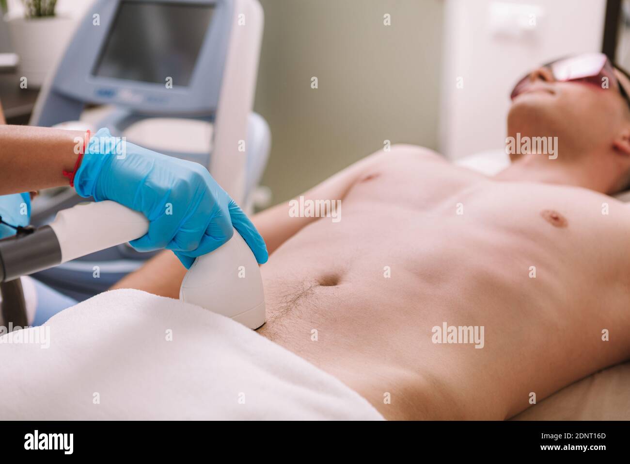 Estetista che rimuove i capelli pubici di un cliente maschio con laser. Uomo che ottiene il trattamento laser di rimozione dei capelli Foto Stock