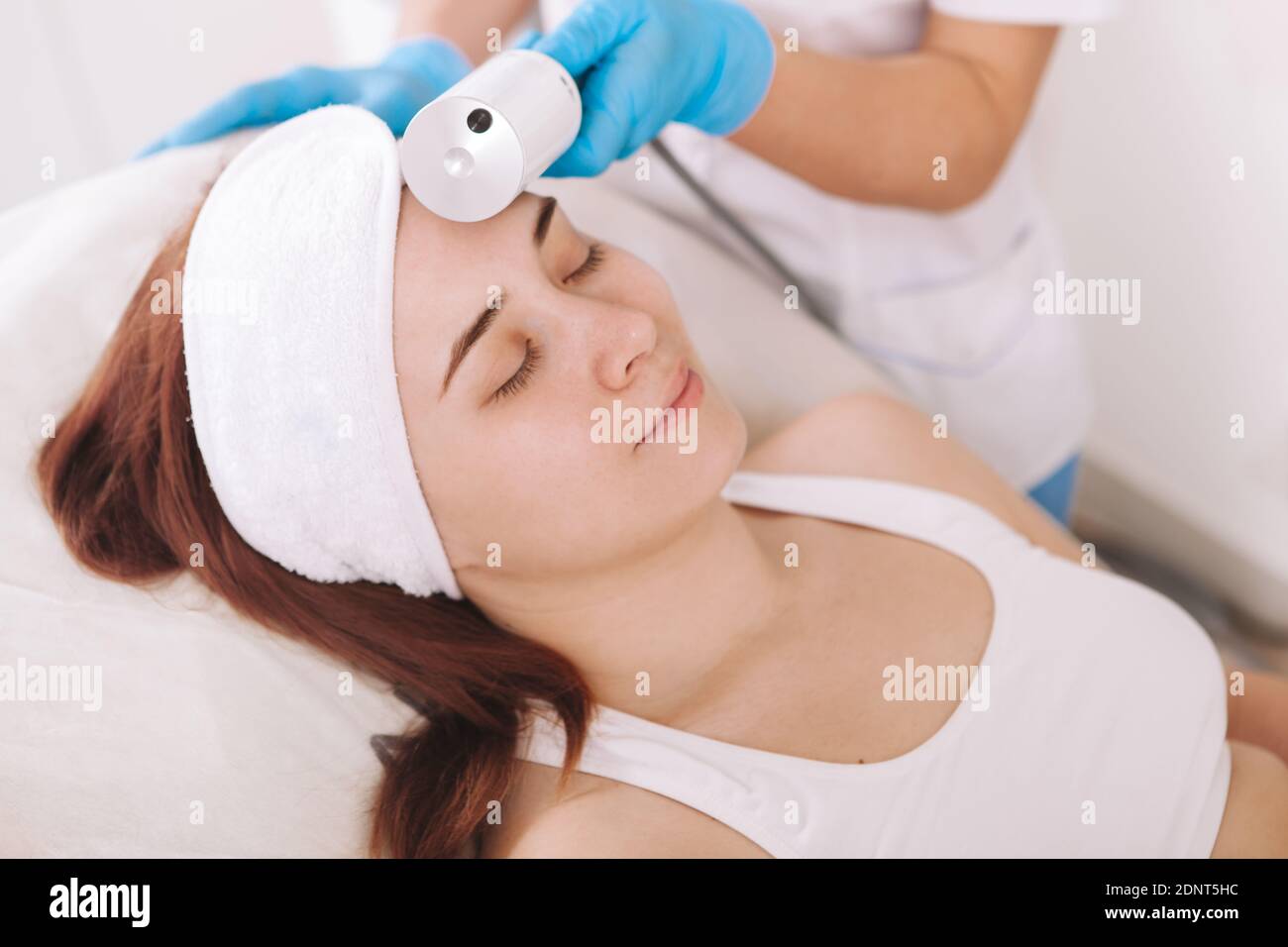 Ripresa tagliata di una giovane donna che gode di trattamento delle endosfere facciali da cosmetologo professionista Foto Stock