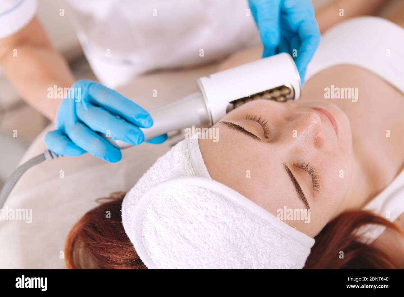 Vista dall'alto ripresa ritagliata di un estetista che fa le endosfere facciali trattamento per cliente femminile Foto Stock
