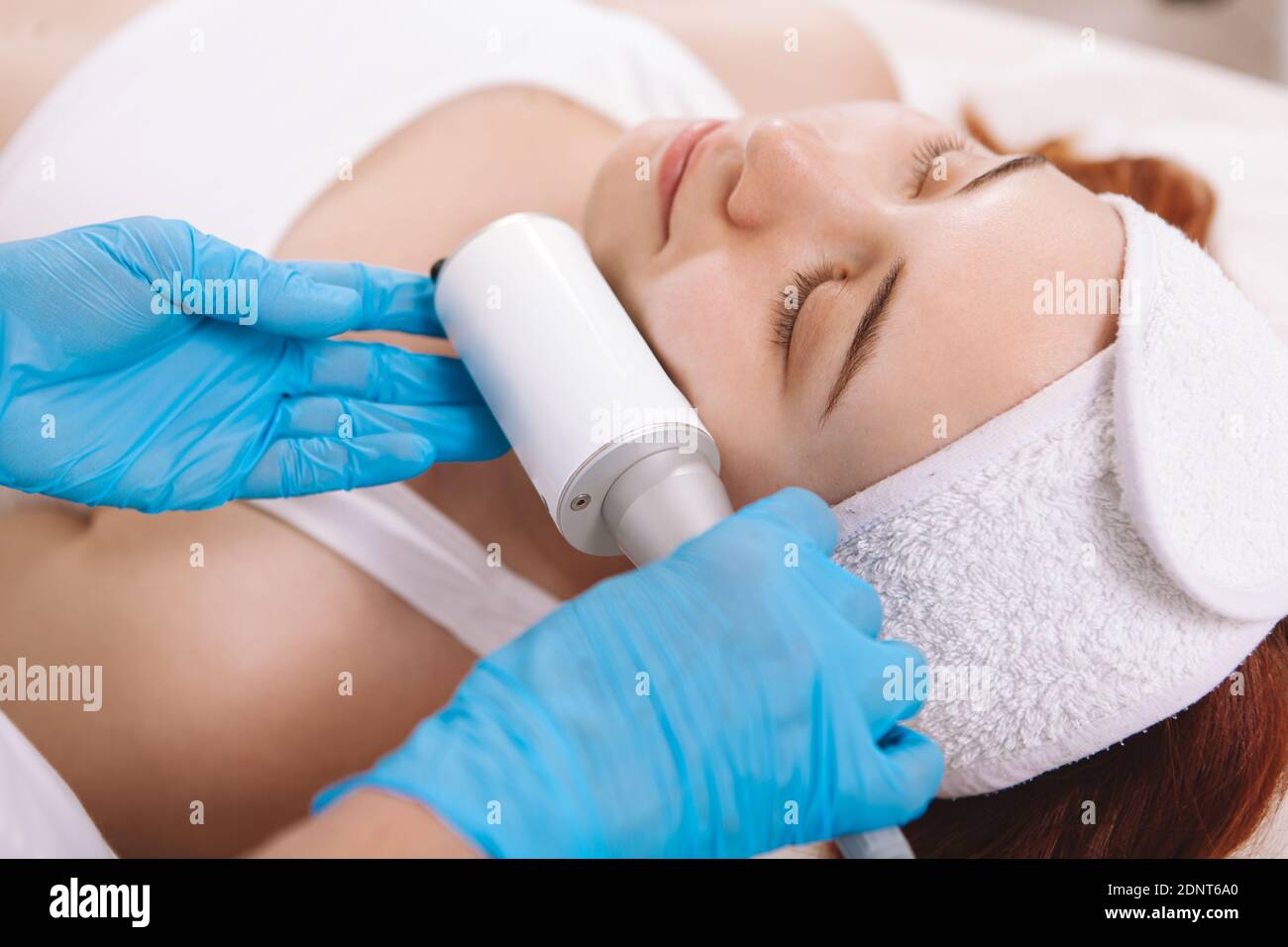 Primo piano di una giovane donna che ottiene rassodamento della pelle e. massaggio di serraggio da estetista Foto Stock