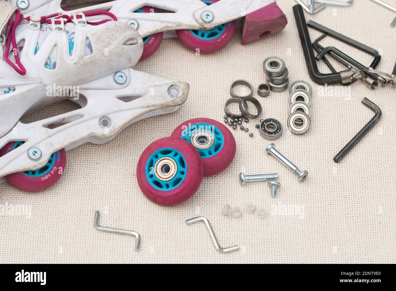 Sostituzione del cuscinetto del pattino a rulli. Pattini a rulli smontati, cuscinetti nuovi e usurati, assali, boccole, viti e chiavi esagonali. Foto Stock