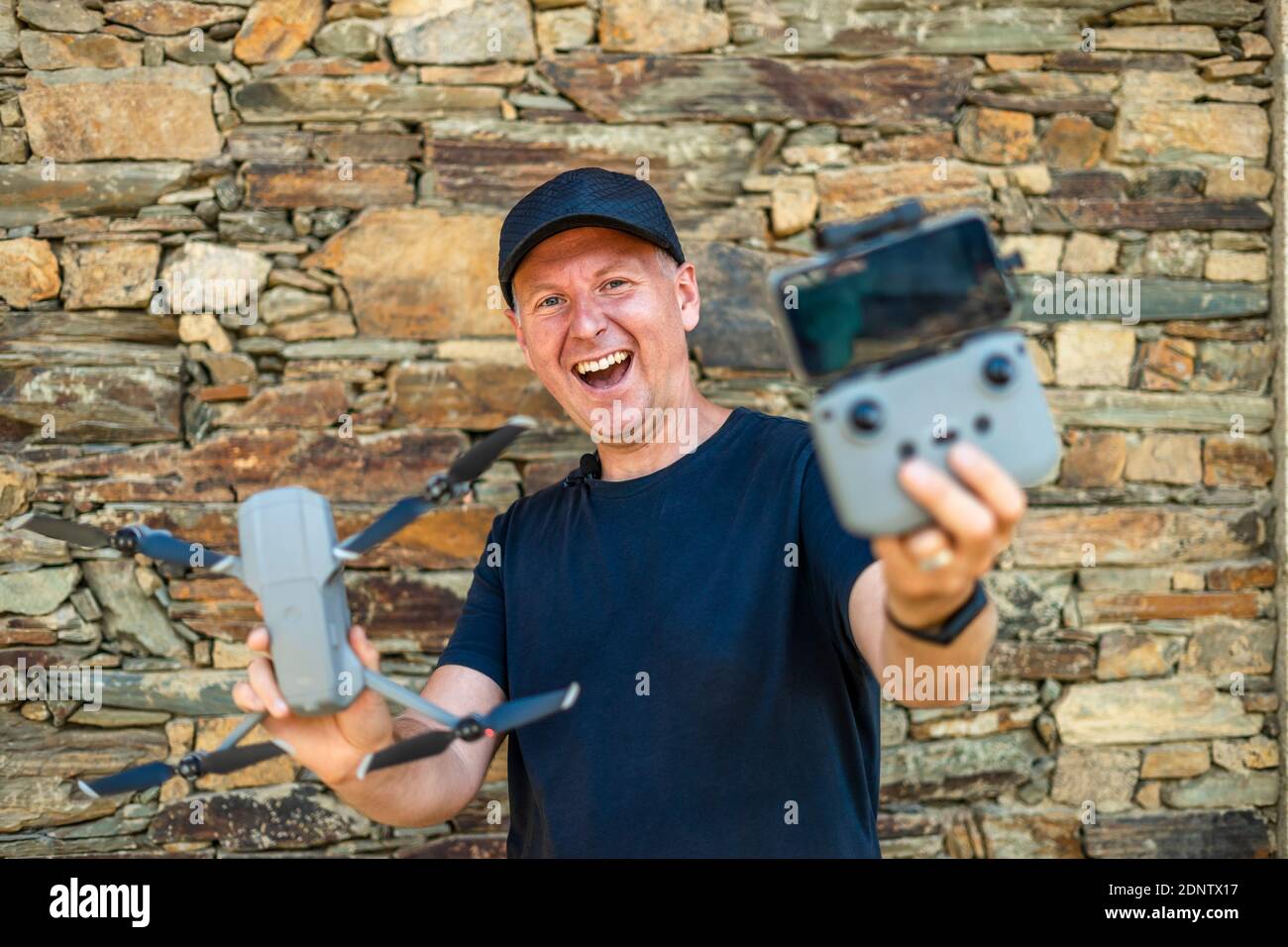 Eccitato uomo che tiene il suo nuovo drone con telecomando e telefono pronto a volare Foto Stock