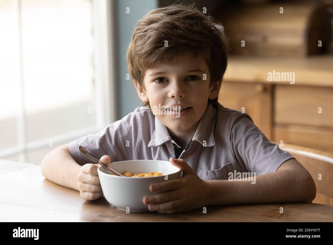 Adorabile ragazzino che ha uno spuntino sano di fiocchi con latte Foto Stock