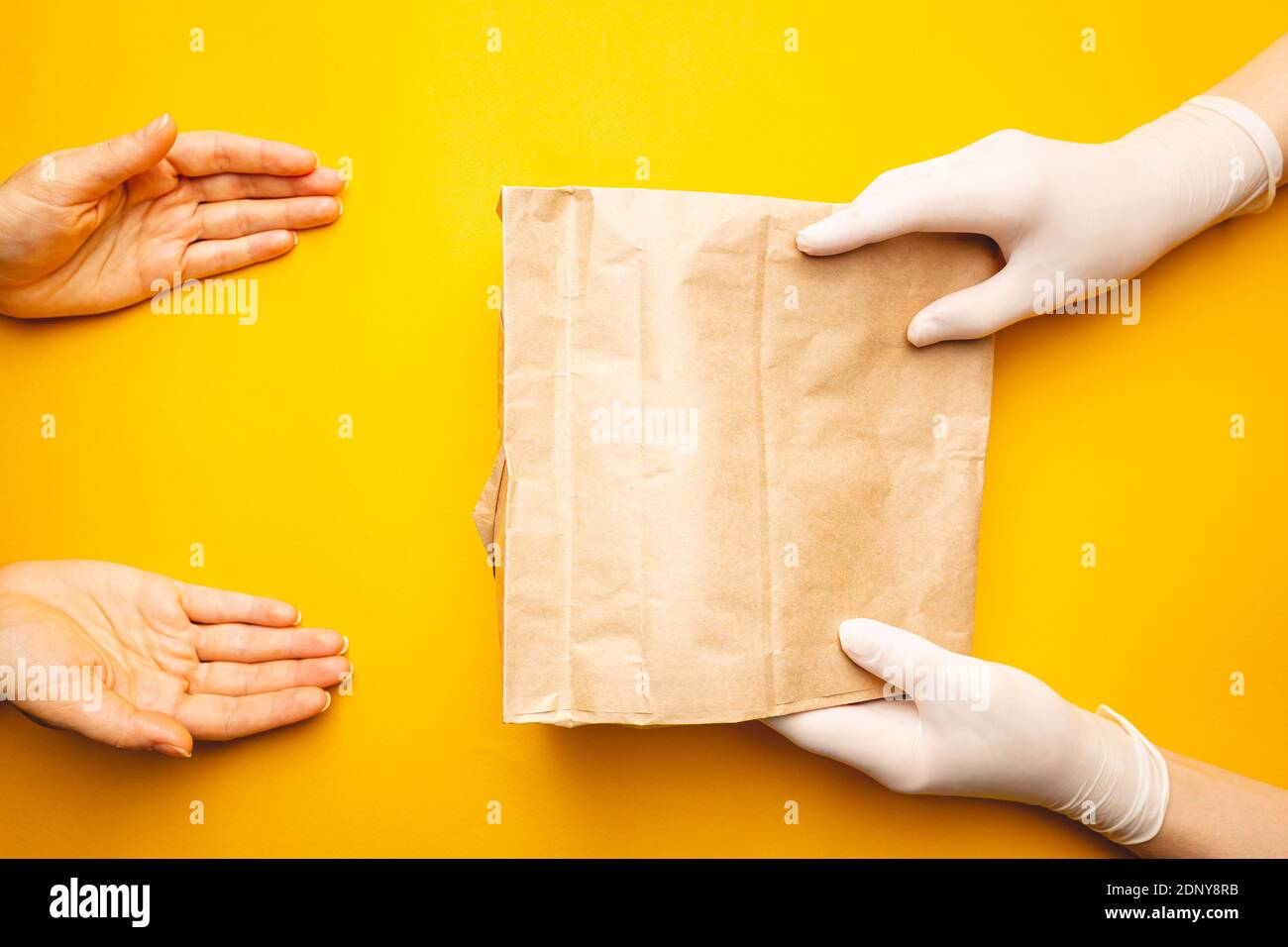 concetto di delivery senza contatto, le mani con guanti trasmettono il pacchetto con protezione contro il virus corona. Consegna sicura tramite corriere Foto Stock
