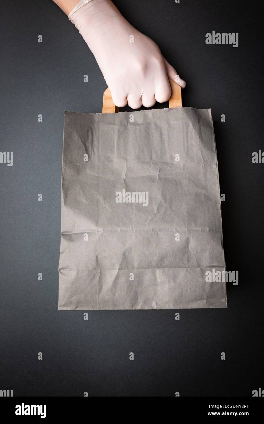 concetto di delivery senza contatto, le mani con guanti trasmettono il pacchetto con protezione contro il virus corona. Consegna sicura tramite corriere Foto Stock