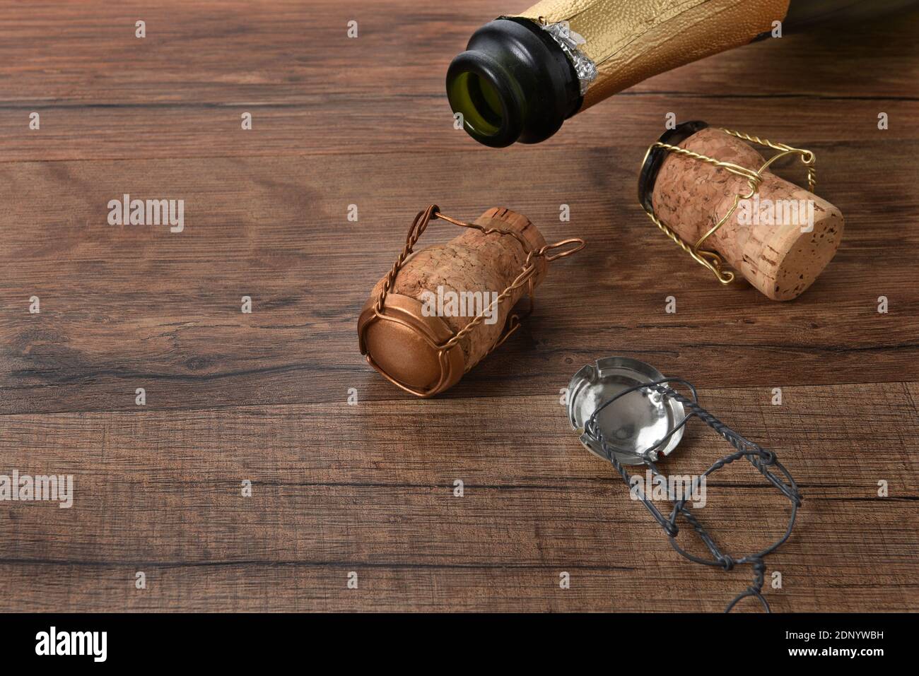 Foto ad alto angolo di una bottiglia di champagne aperta con tappi su un tavolo di legno con spazio per la copia. Foto Stock
