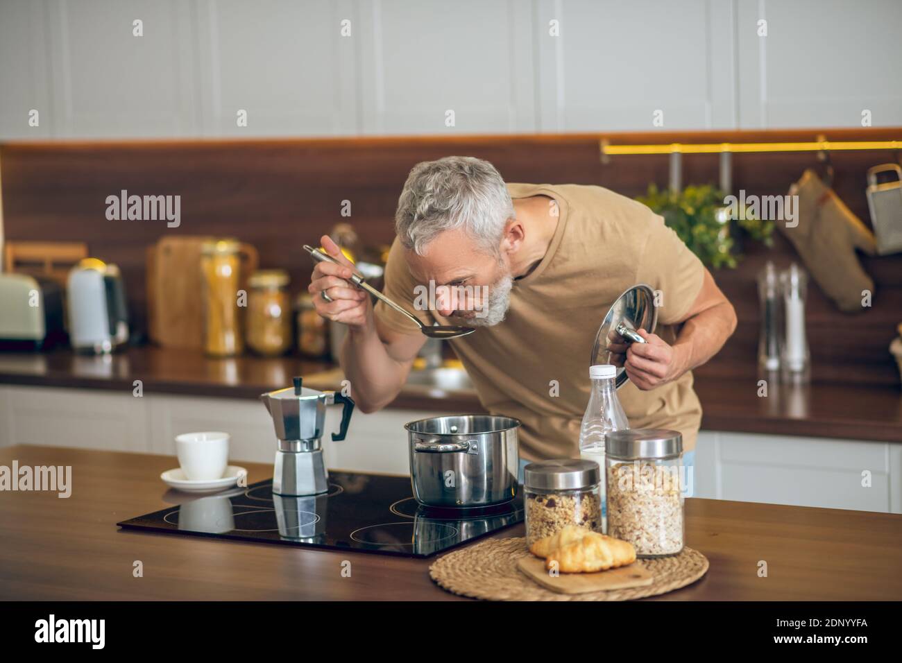 Uomo maturo in tshirt beige cucina Foto Stock