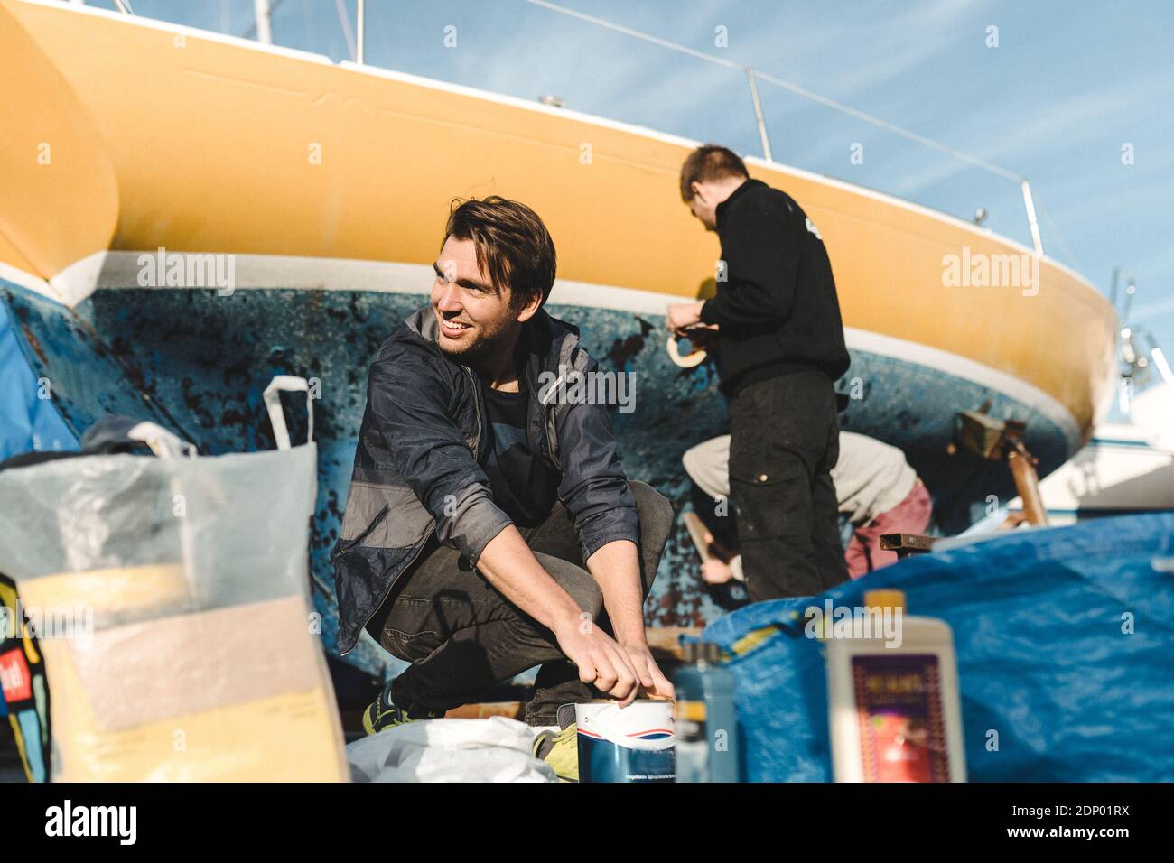 Amici che preparano la barca per la pittura Foto Stock
