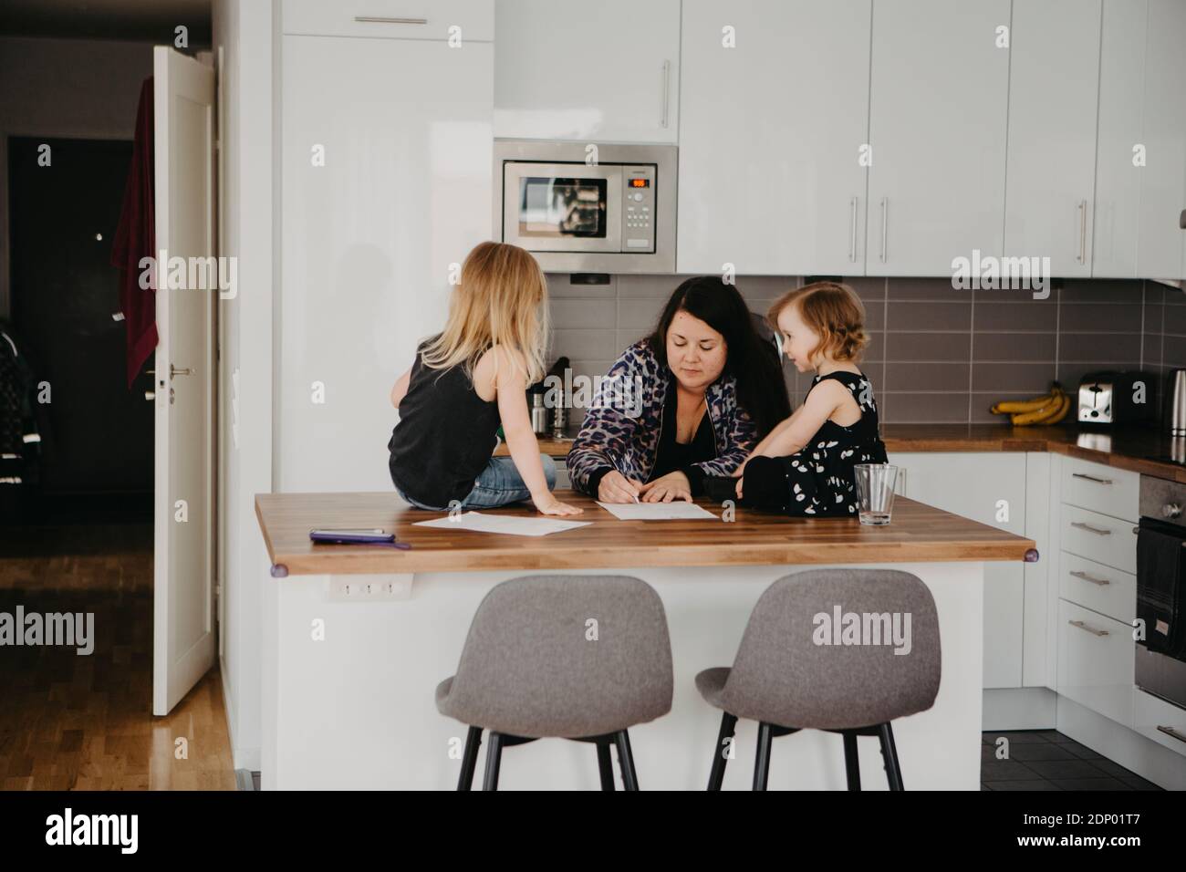 Donna con due figlie in cucina Foto Stock