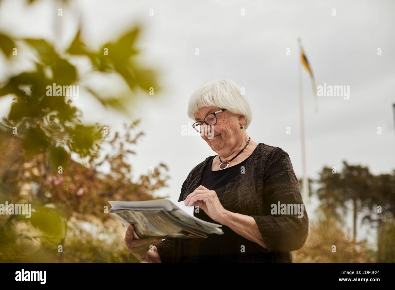 Donna anziana che tiene il giornale Foto Stock