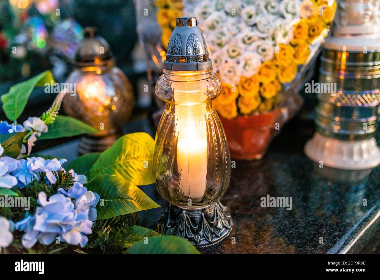 Fiori artificiali e candelabri giacciono sulla Tombstone nel Cimitero. Foto Stock