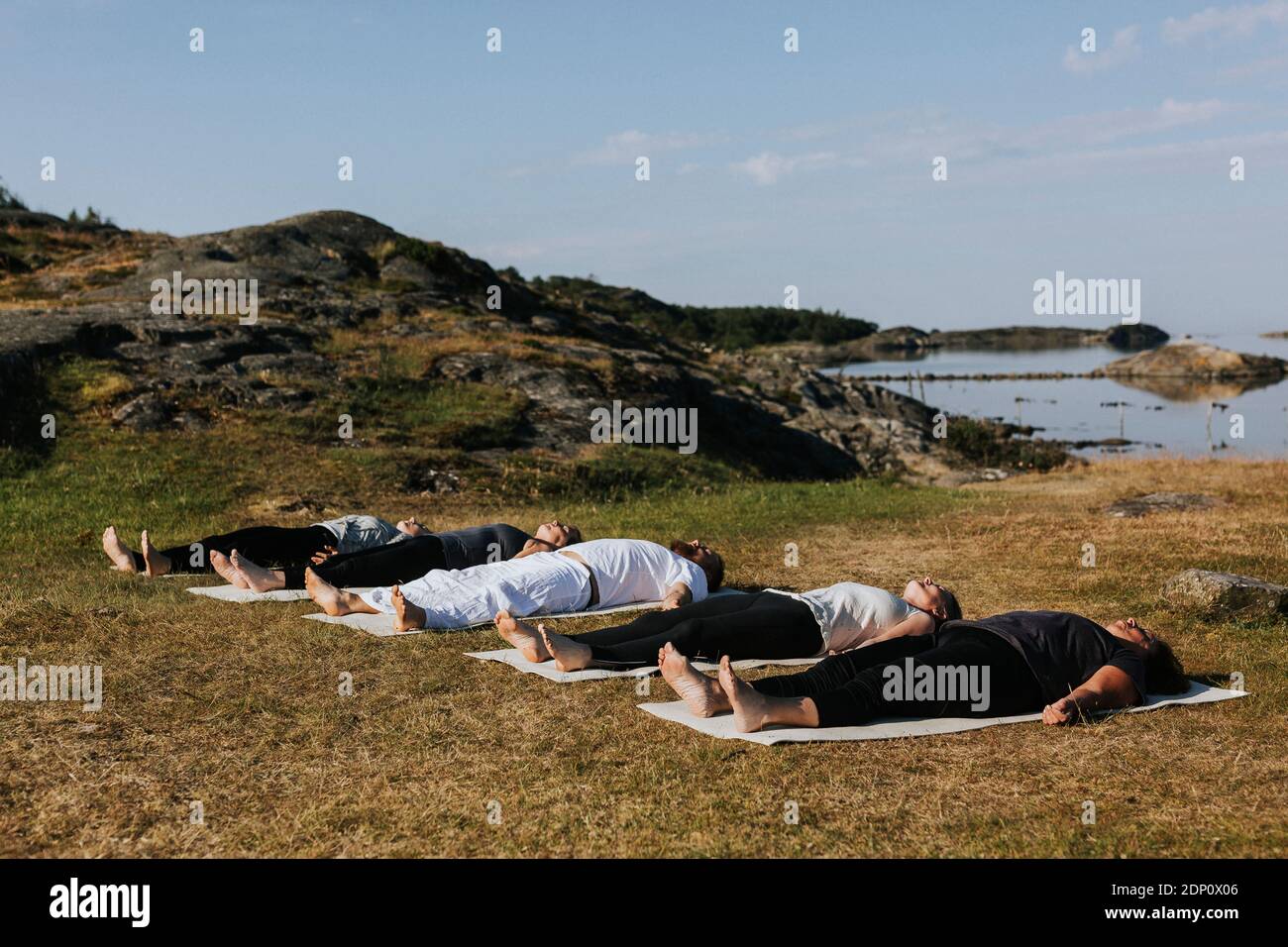 Persone che praticano yoga sulla costa Foto Stock