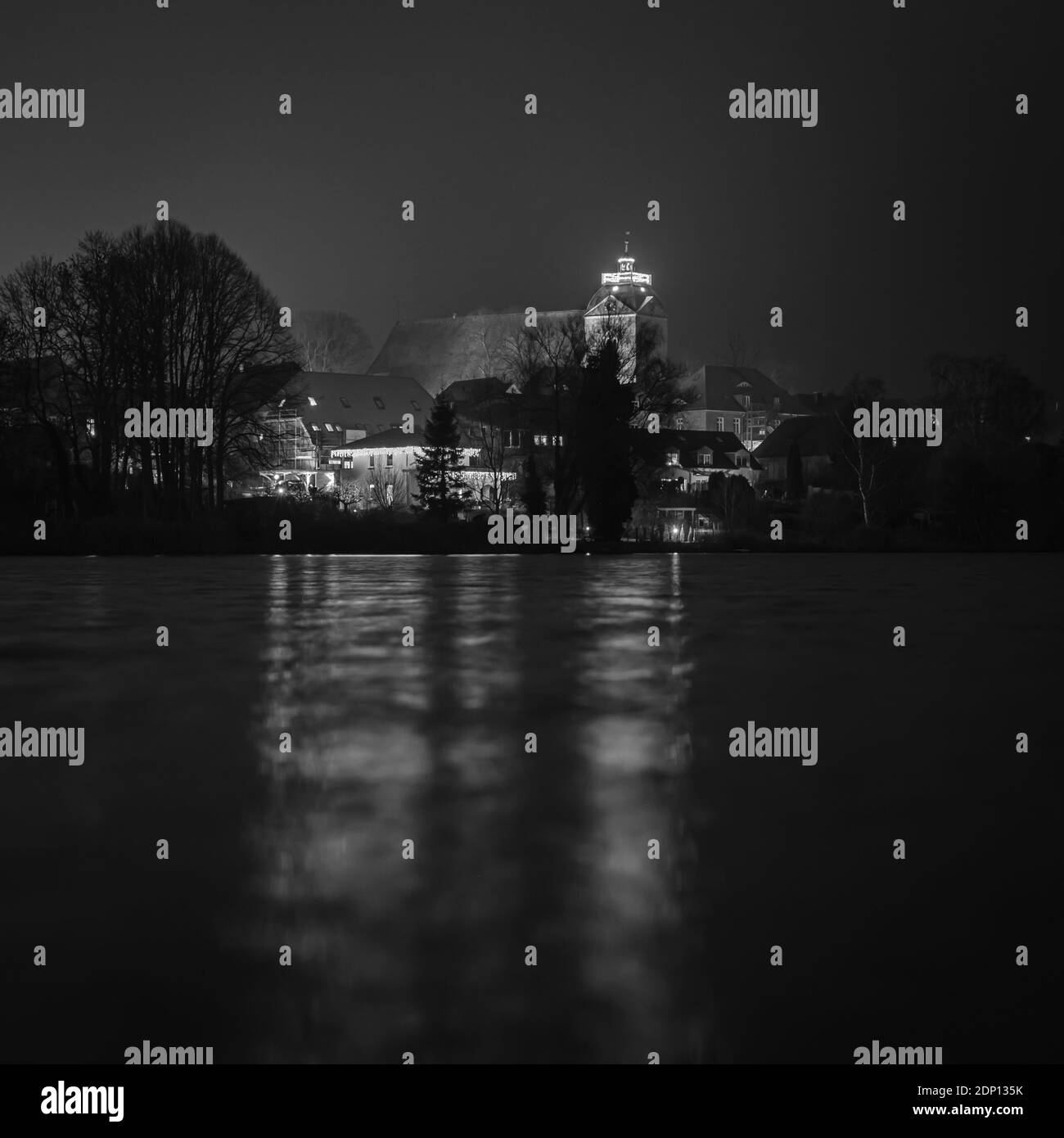 Le luci di Natale di una chiesa riflesse in un lago al buio Foto Stock