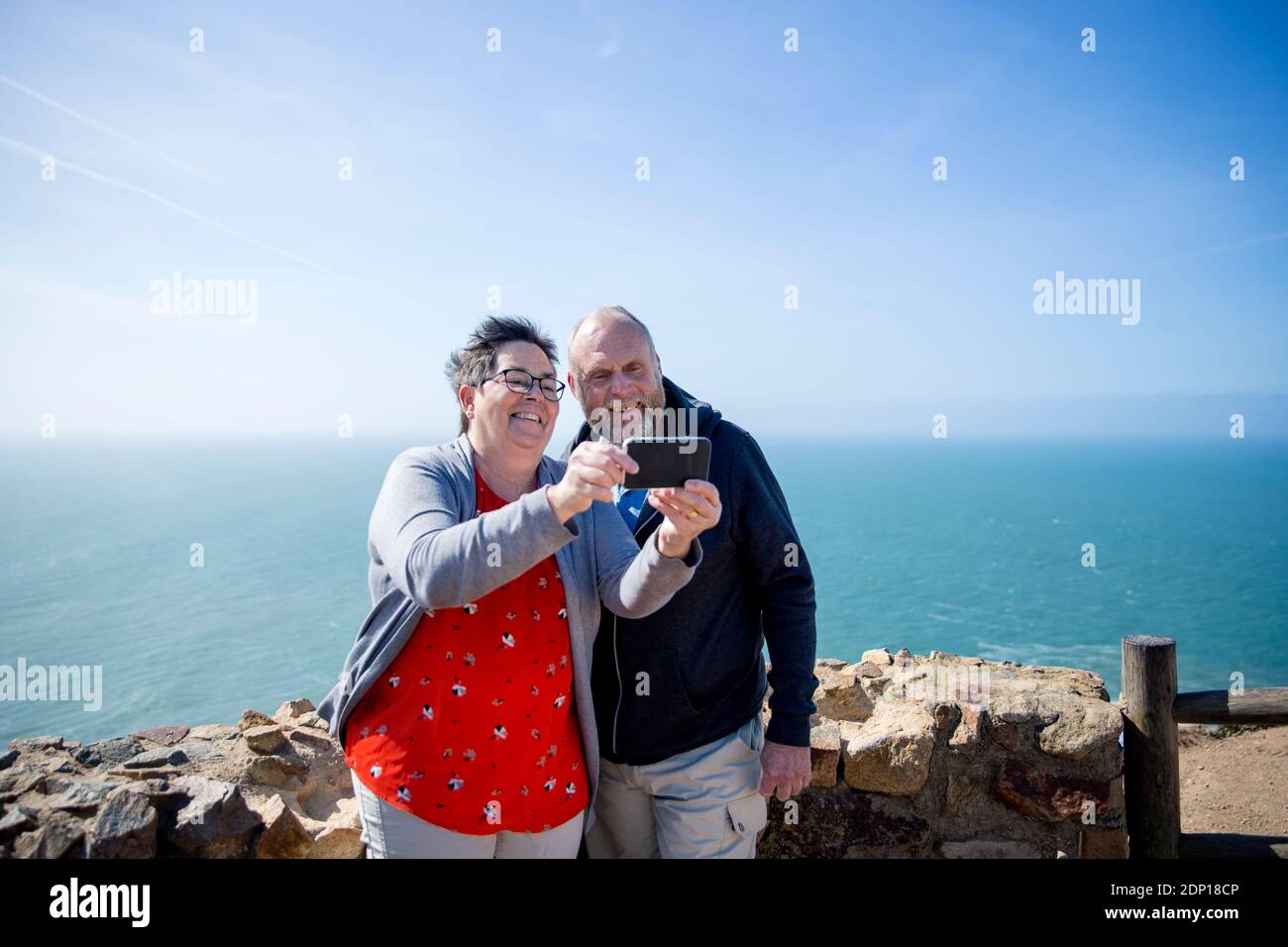Coppia sorridente che prende selfie, mare su sfondo Foto Stock