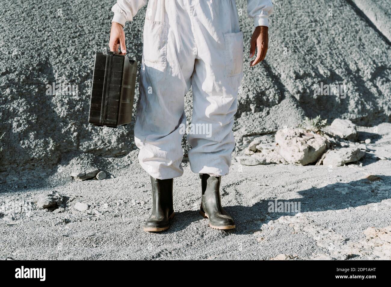Uomo con valigia in piedi in un paesaggio asciutto Foto Stock