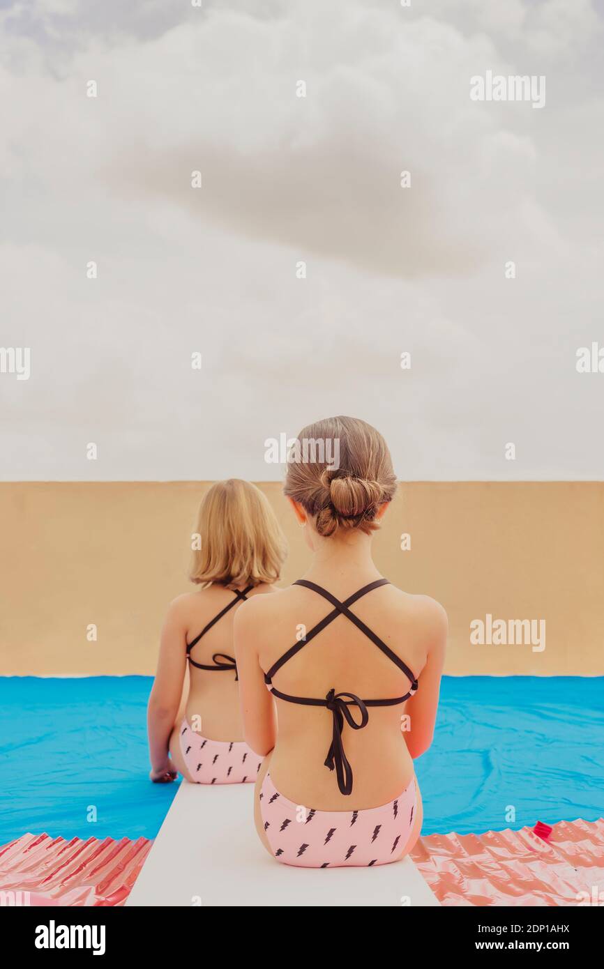 Vista posteriore di due ragazze che giocano piscina sulla terrazza sul tetto Foto Stock