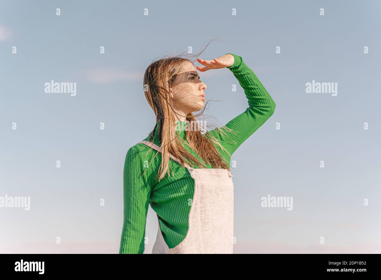 Giovane donna che scherma gli occhi contro il sole Foto Stock