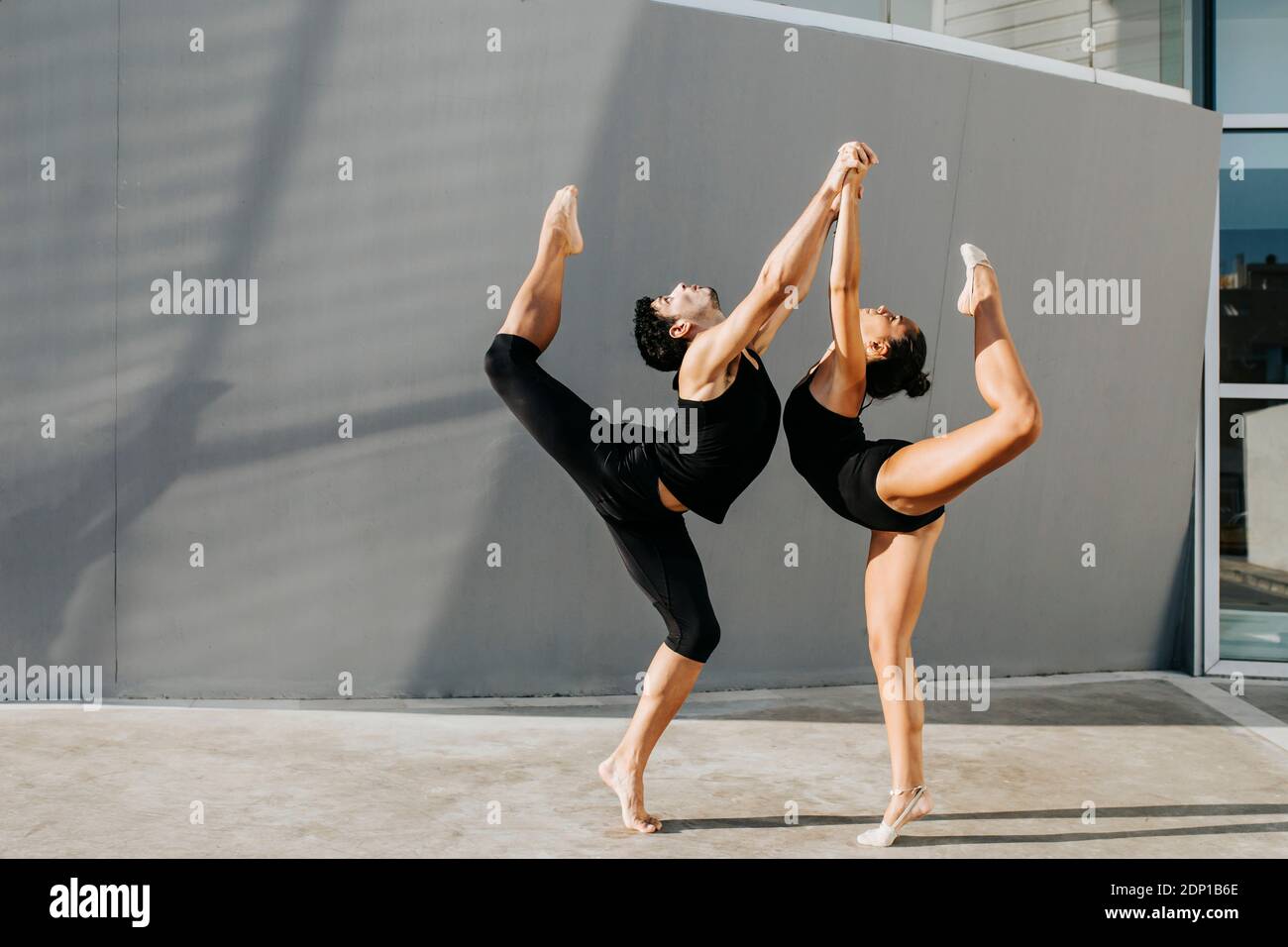 Ginnasti professionali in piedi su una gamba mentre equilibrano da grigio parete Foto Stock