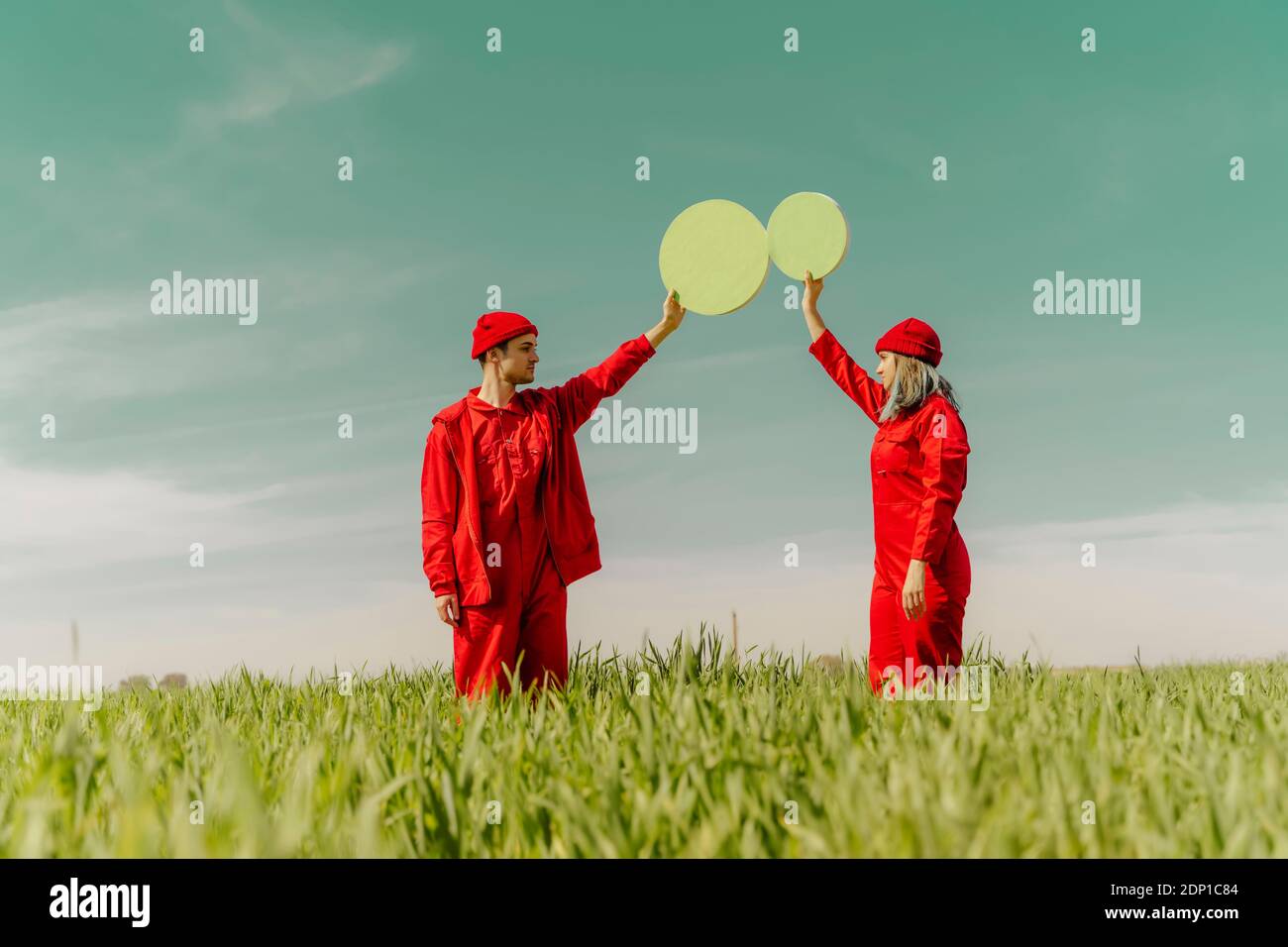 Giovane coppia che indossa tute rosse in piedi su una tenuta di campo due cerchi verdi Foto Stock