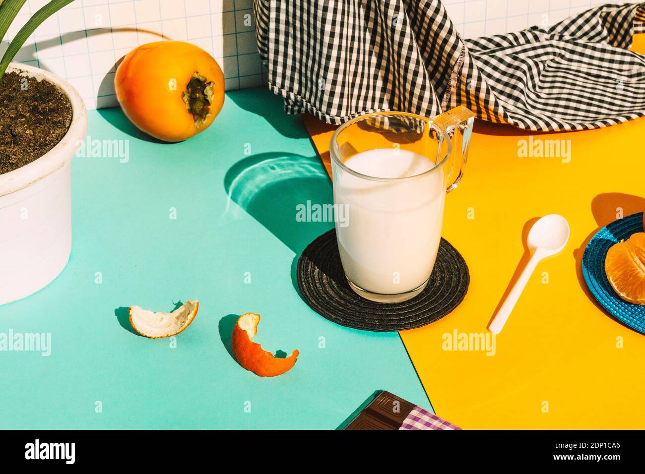 Tazza di latte con tovagliolo e frutta su tavolo multicolore Foto Stock