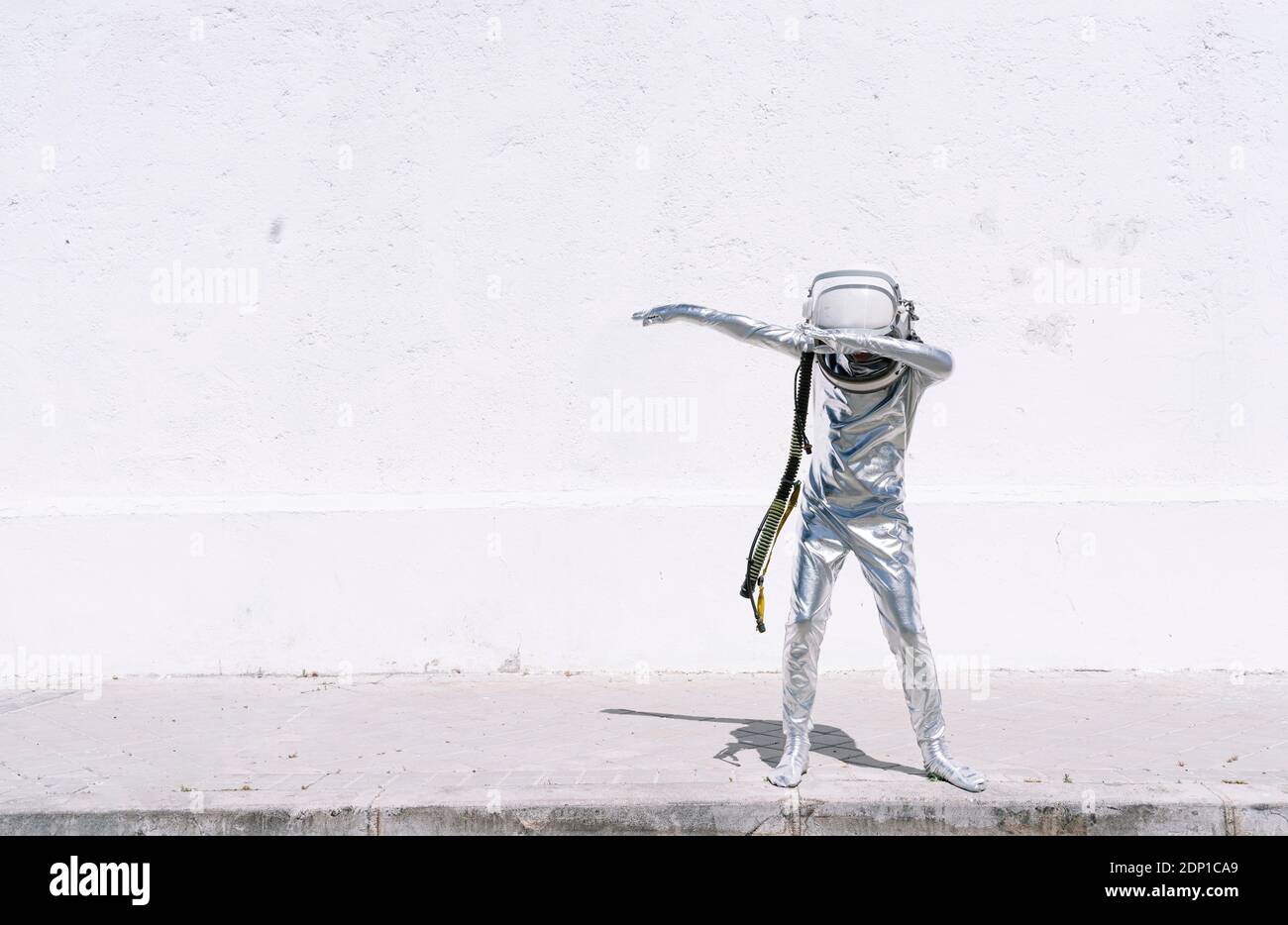 Ragazzo in costume astronauta dabbing movimento mentre in piedi contro muro Foto Stock