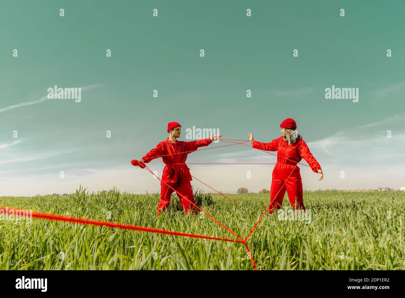 Giovane coppia che indossa tute rosse e cappelli che si esibiscono su un campo con stringa rossa Foto Stock
