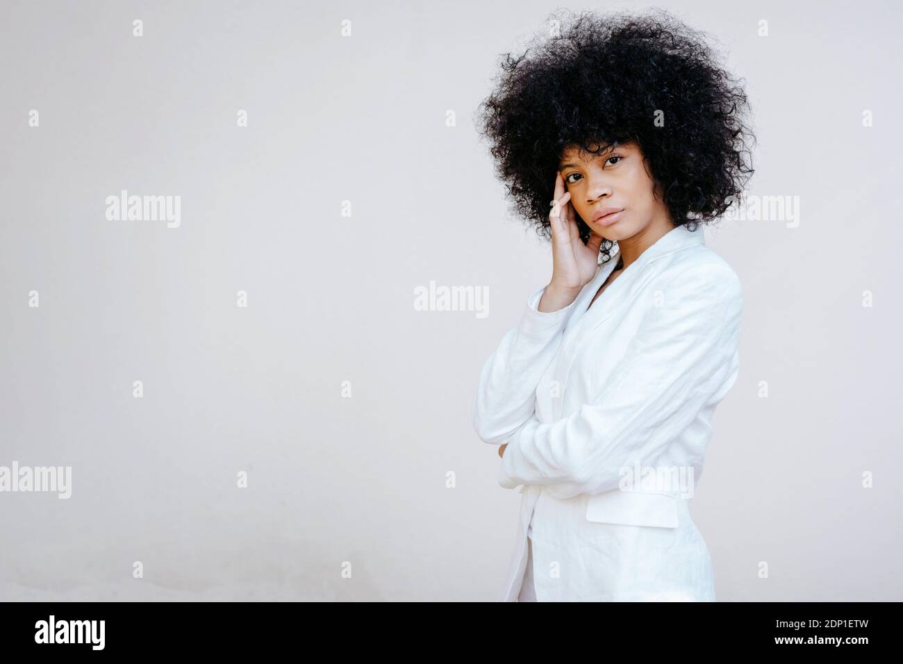 Ritratto di donna afroamericana con capelli afro vestito bianco davanti al muro urbano bianco di Granada, Spagna Foto Stock