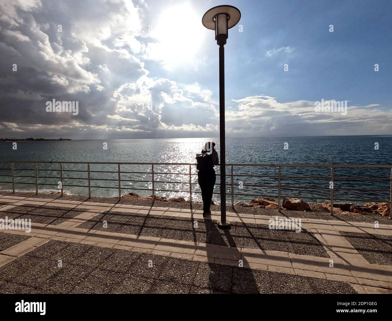 Donna sola che gode della vista sul mare in un giorno luminoso di dicembre vicino Atene, Grecia Foto Stock