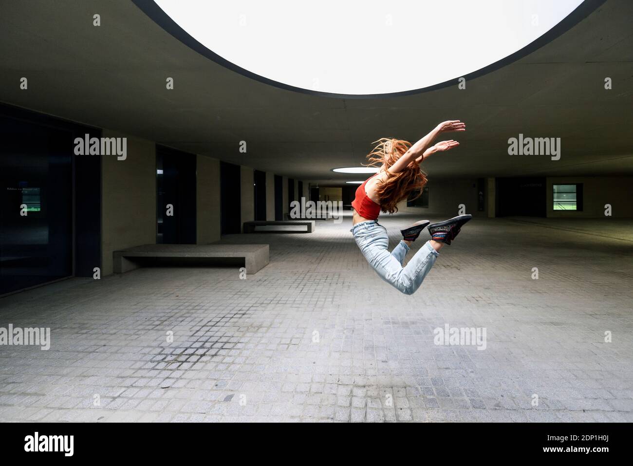 Giovane donna sportiva che salta in cortile Foto Stock