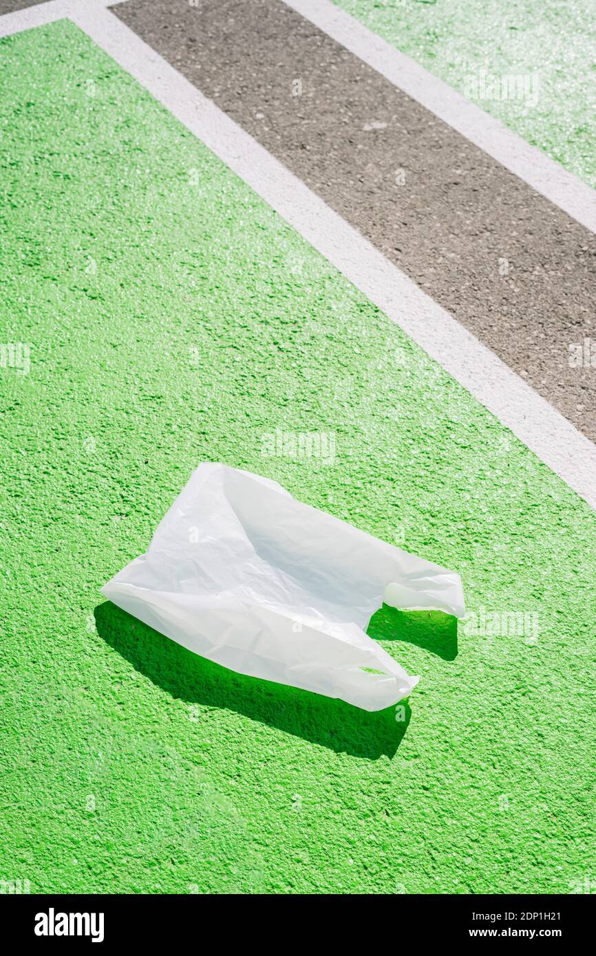 Borsa di plastica sul sentiero verde durante la giornata di sole Foto Stock