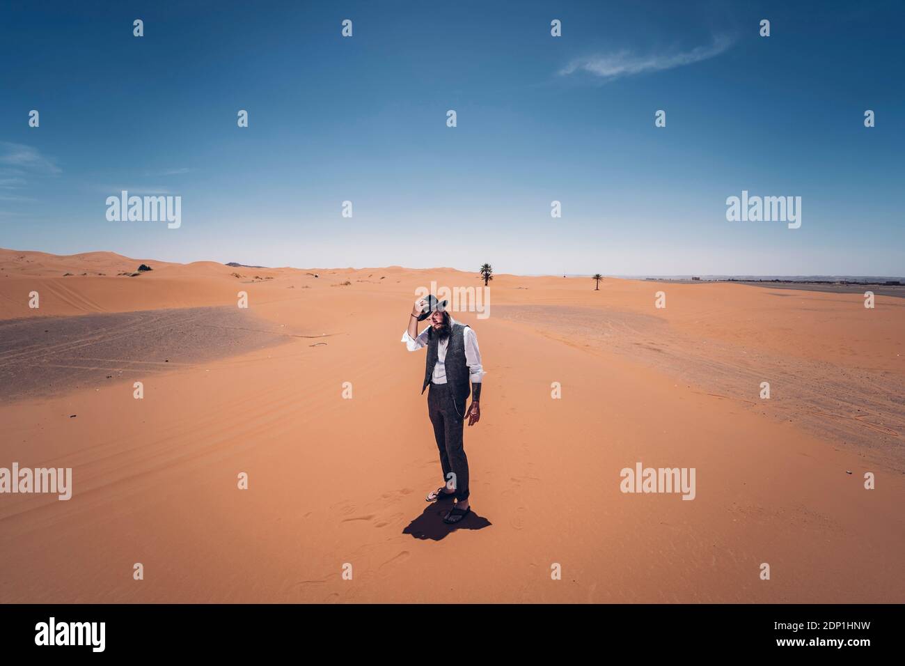 Uomo con la barba e hat nelle dune del deserto del Marocco Foto Stock