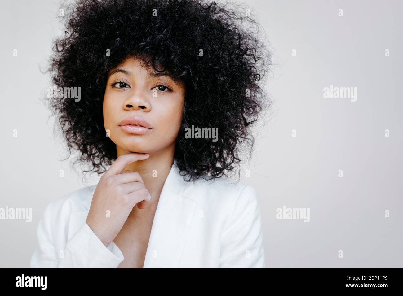Ritratto di donna afroamericana con capelli afro vestito bianco davanti al muro urbano bianco di Granada, Spagna Foto Stock