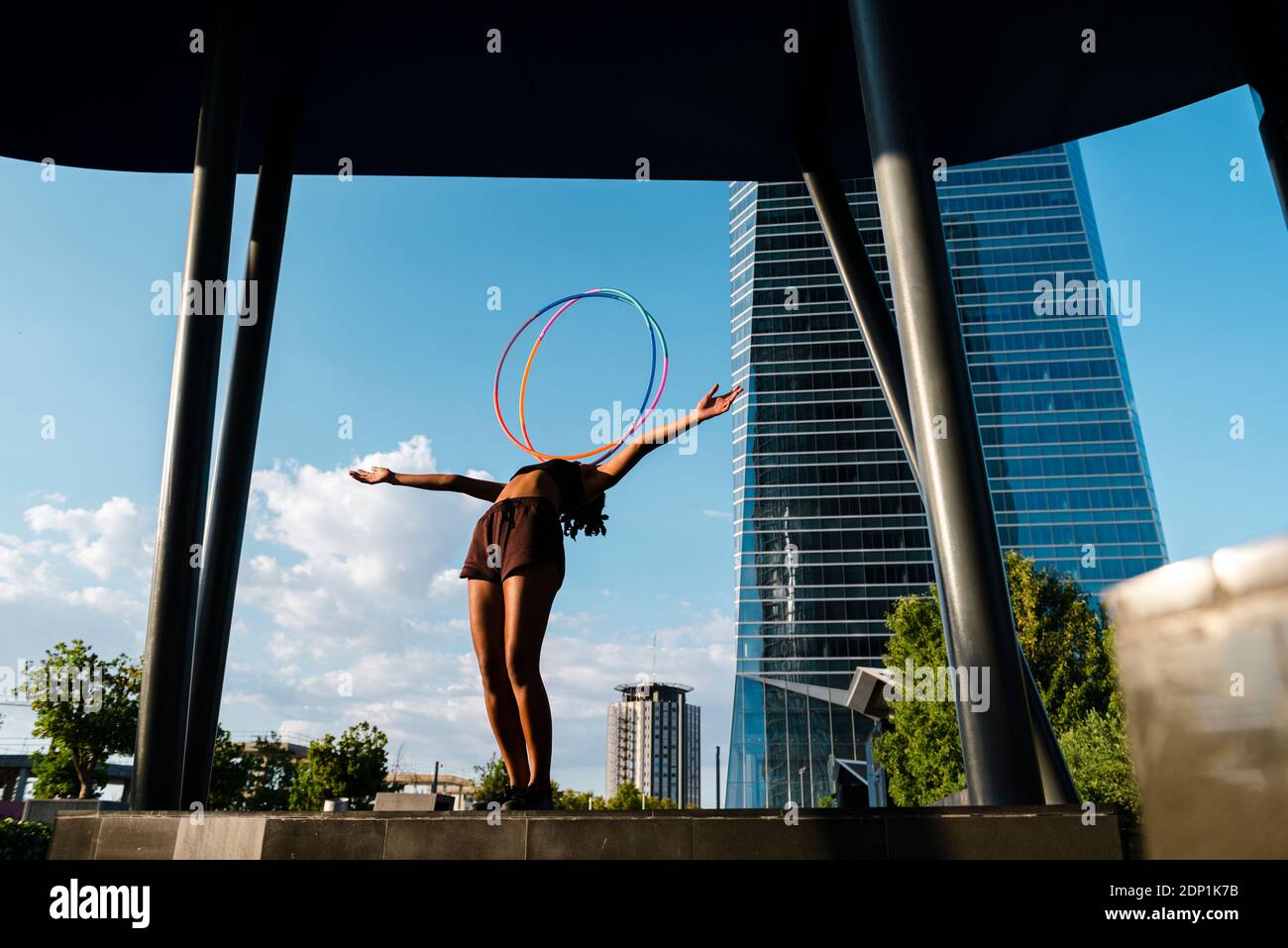 Donna sportiva che bilancia i cerchi in plastica sul petto nella città moderna Foto Stock