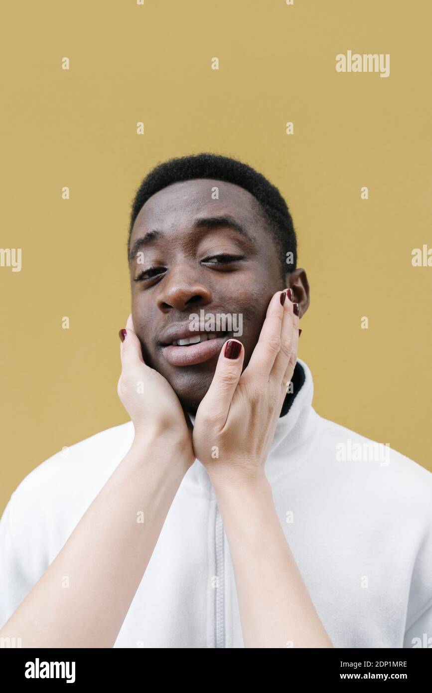 Ritratto di un uomo sorridente toccato dalle mani della donna Foto Stock