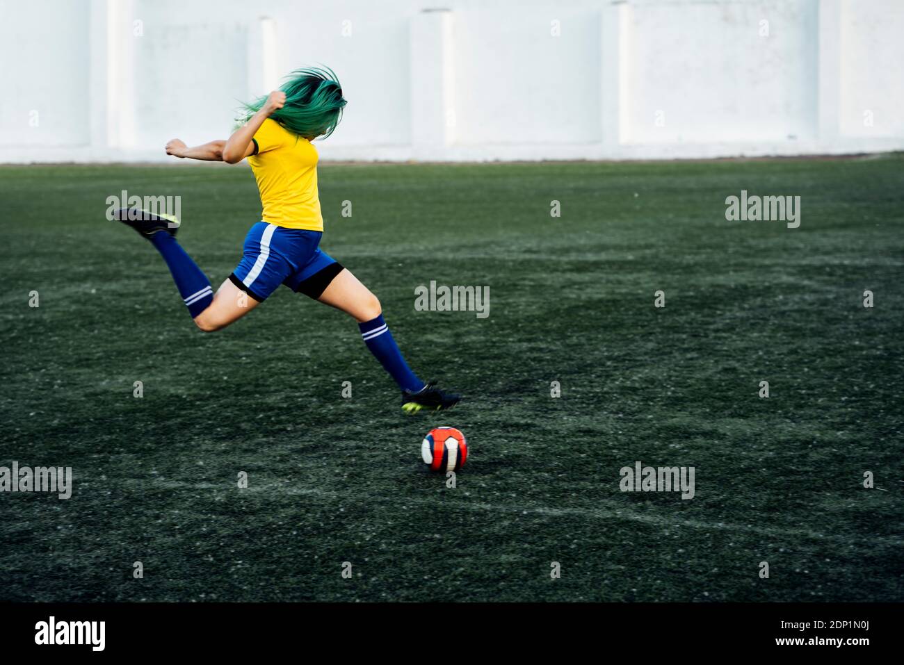 Giovane donna a giocare il gioco del calcio sul terreno di calcio tiro della palla Foto Stock