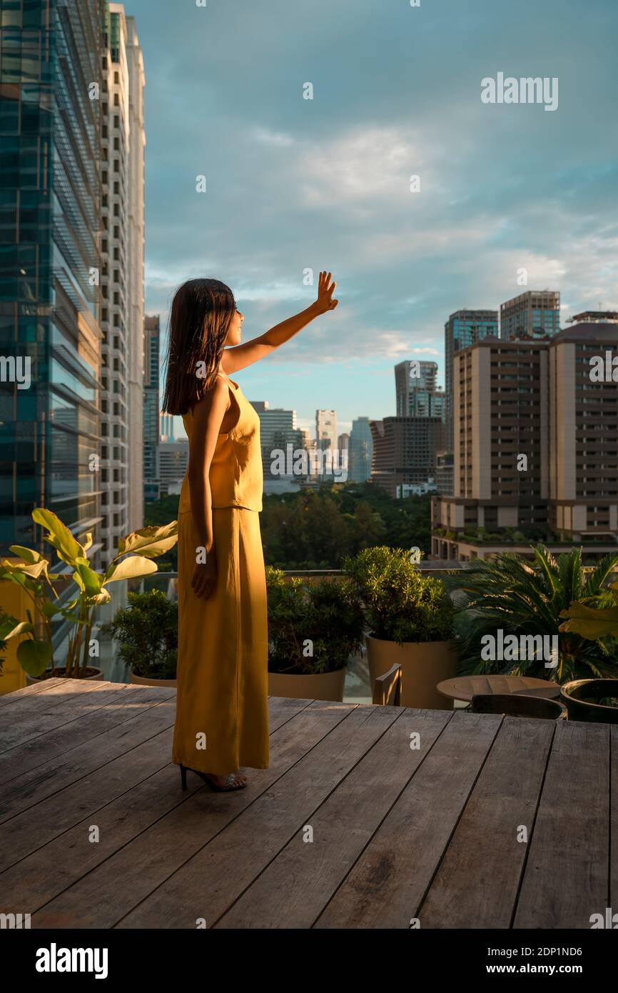 Donna in piedi sulla terrazza sul tetto a luce solare, Bangkok, Thailandia Foto Stock