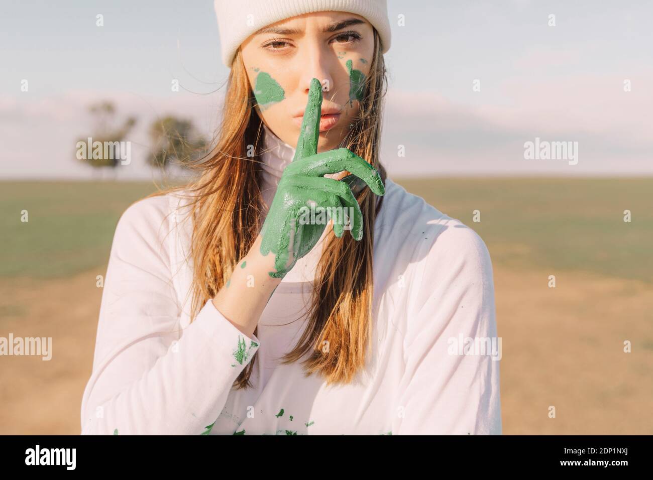Giovane donna che mette un dito di mano verde sulla bocca Foto Stock