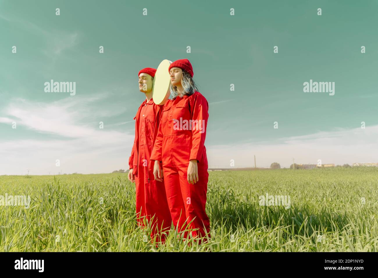 Giovane coppia che indossa tute rosse in piedi su un campo con cerchio verde Foto Stock