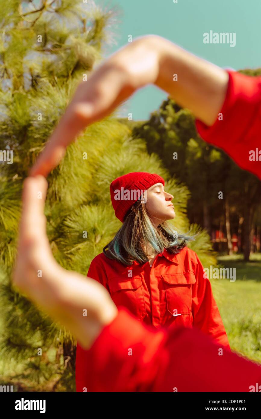 Giovane donna vestita di rosso che gode della luce del sole nella natura Foto Stock