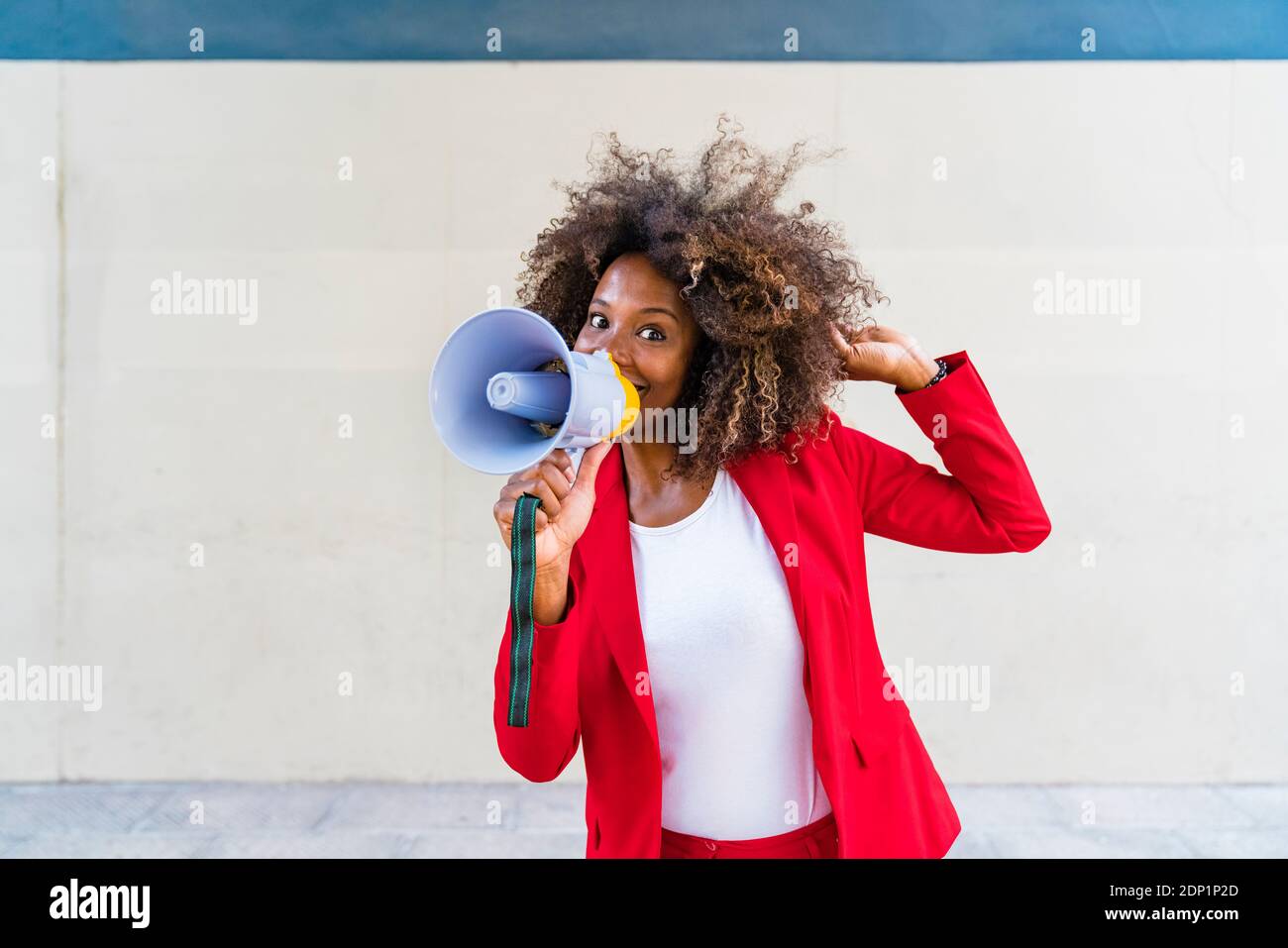 Donna mid adulta che usa il megafono mentre si trova contro il muro Foto Stock