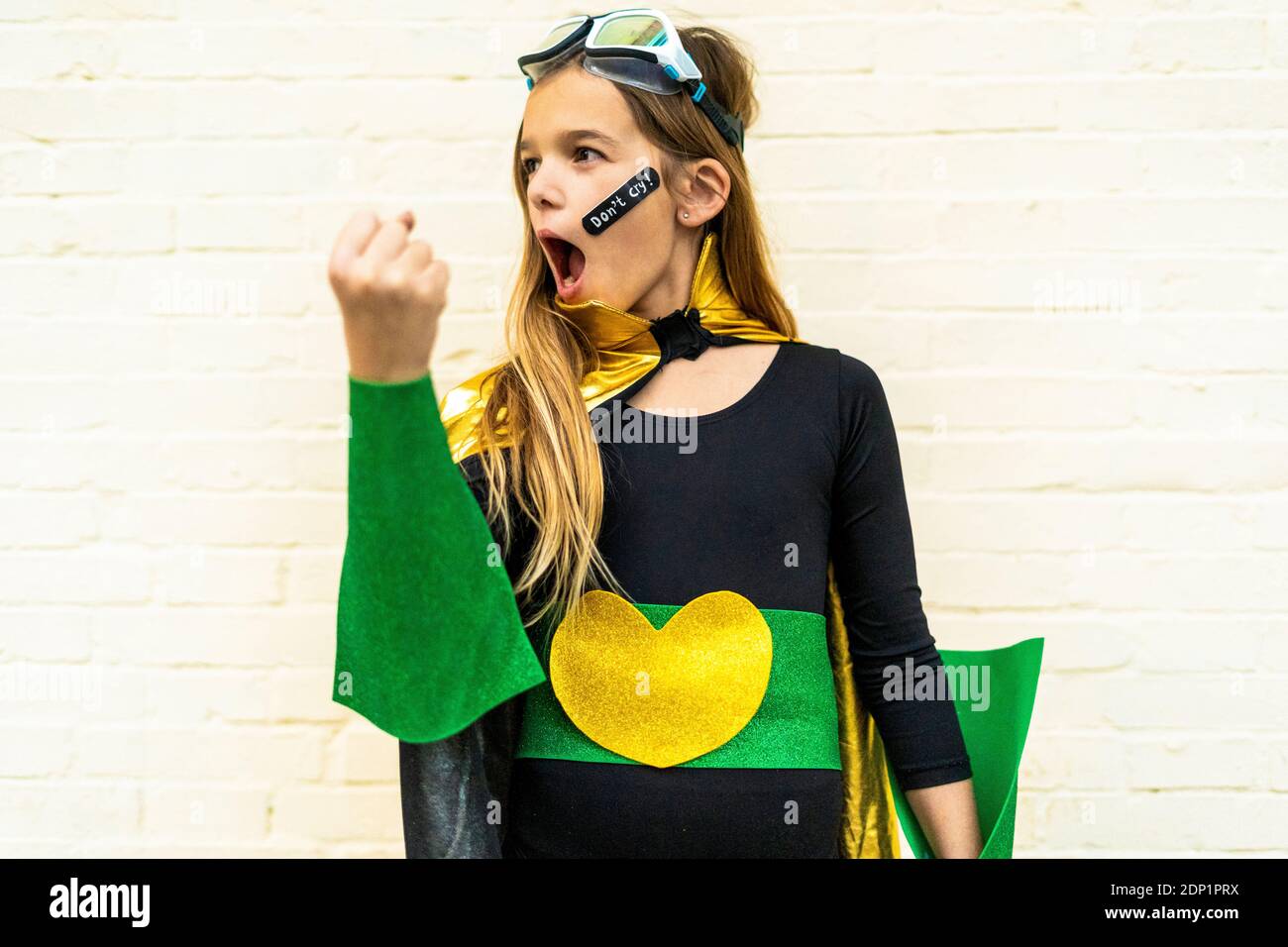 La ragazza di super eroina costume con band-aiuto sulla guancia Foto Stock