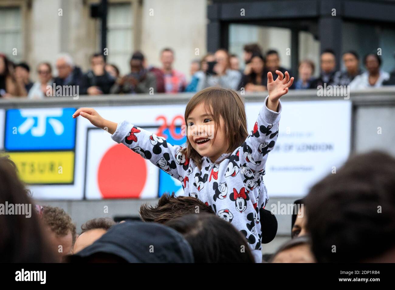 Un bambino ride e guarda le performance al Japan Matsuri Festival di Trafalgar Square, Londra, Regno Unito Foto Stock