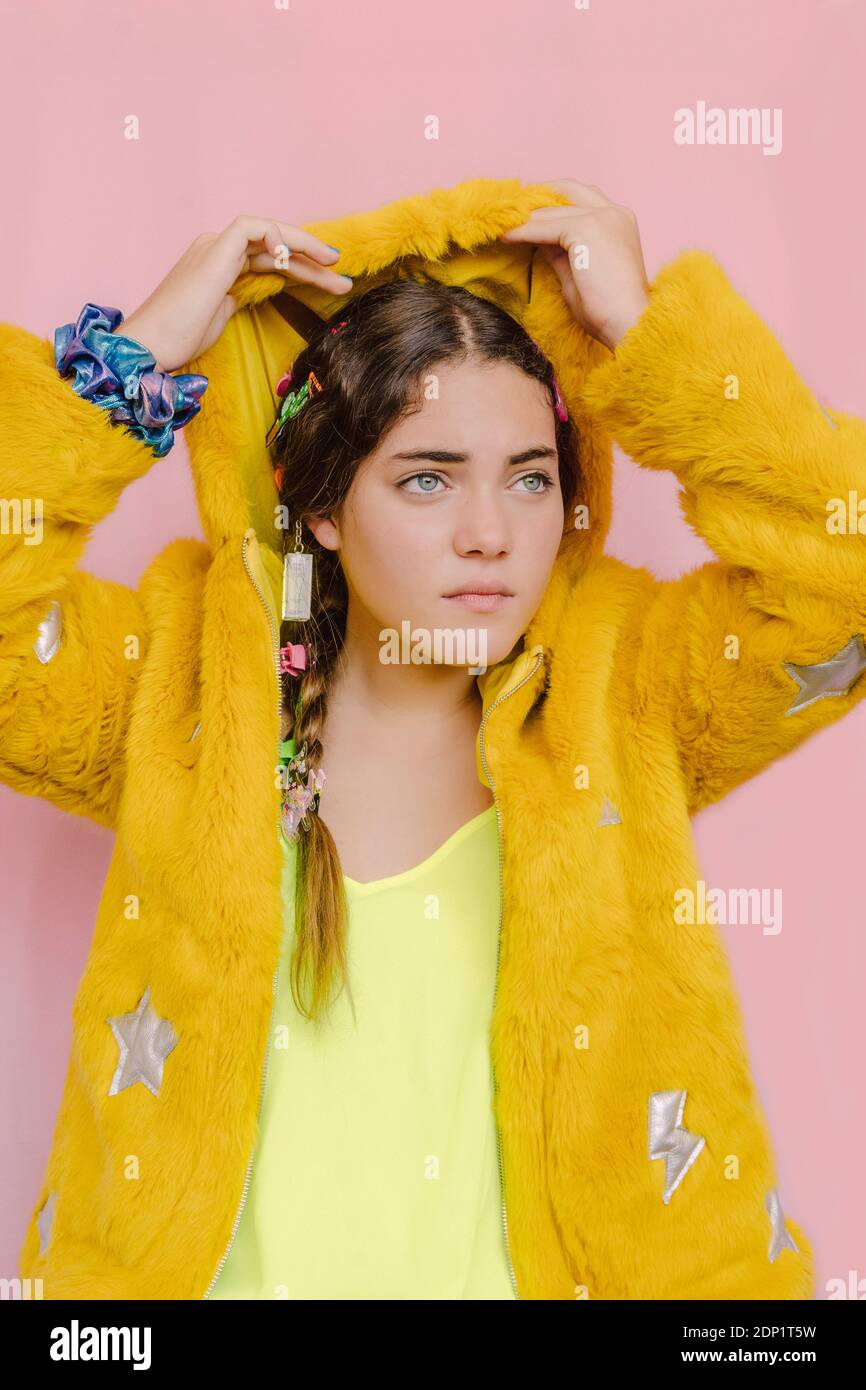 Ragazza adolescente che indossa il cappuccio della sua giacca gialla di peluche Foto Stock